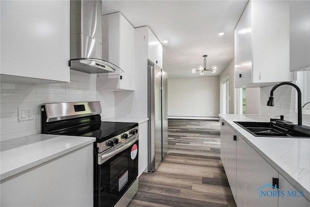 kitchen with stainless steel appliances, wall chimney range hood, a sink, white cabinetry, and recessed lighting