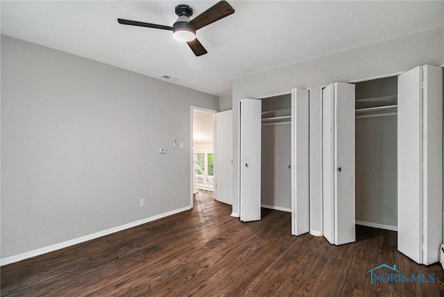 unfurnished bedroom with two closets, wood finished floors, baseboards, and a ceiling fan