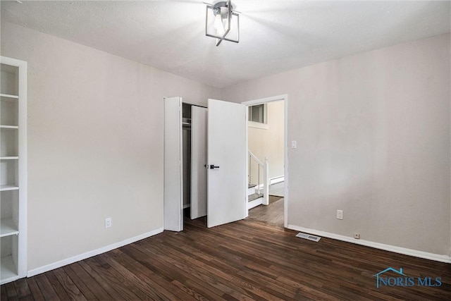 unfurnished bedroom with wood finished floors, baseboards, and a closet