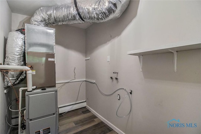 laundry room featuring dark wood-style flooring, a baseboard heating unit, and heating unit