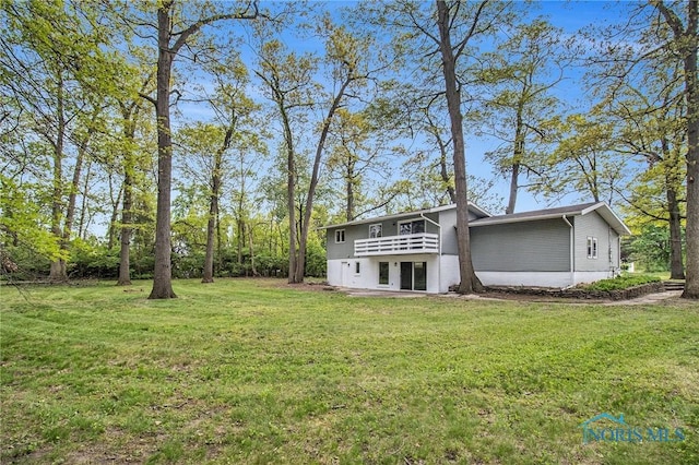view of green lawn featuring a balcony