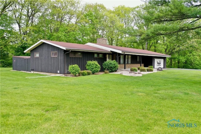 230 Orchard Ln, Upper Sandusky, OH 43351 - rear view of house featuring board and batten siding, a chimney, and a yard