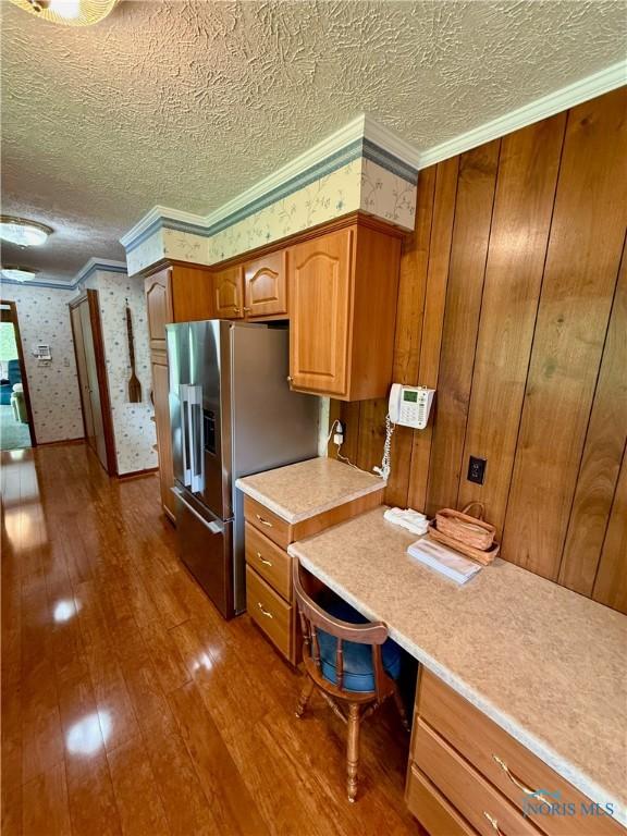 230 Orchard Ln, Upper Sandusky, OH 43351 - kitchen featuring dark wood-type flooring, stainless steel fridge with ice dispenser, brown cabinets, wallpapered walls, and ornamental molding
