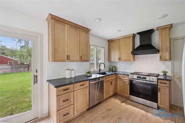 800 Pierce St, Maumee, OH 43537 - kitchen with stainless steel appliances, wall chimney exhaust hood, a sink, dark countertops, and light wood-type flooring