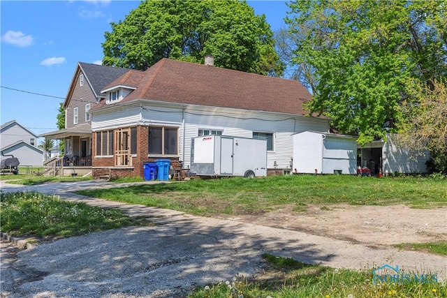 view of front facade featuring a chimney, brick siding, and a shingled roof