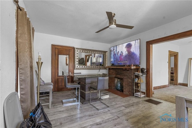 bar with wood finished floors, ceiling fan, a textured ceiling, and baseboards