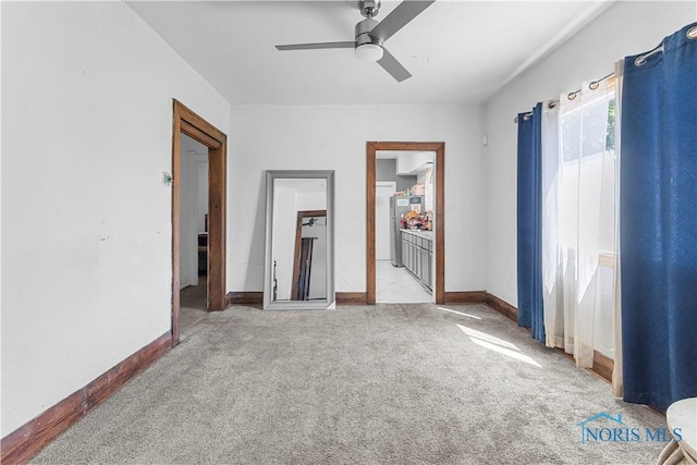 unfurnished bedroom with light colored carpet, baseboards, ensuite bathroom, and ceiling fan
