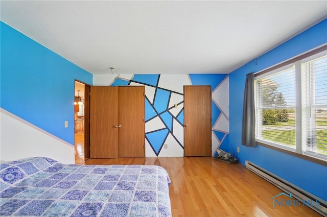 5450 Twp Rd 69, Tiffin, OH 44883 - bedroom featuring a baseboard heating unit, wood finished floors, and multiple windows