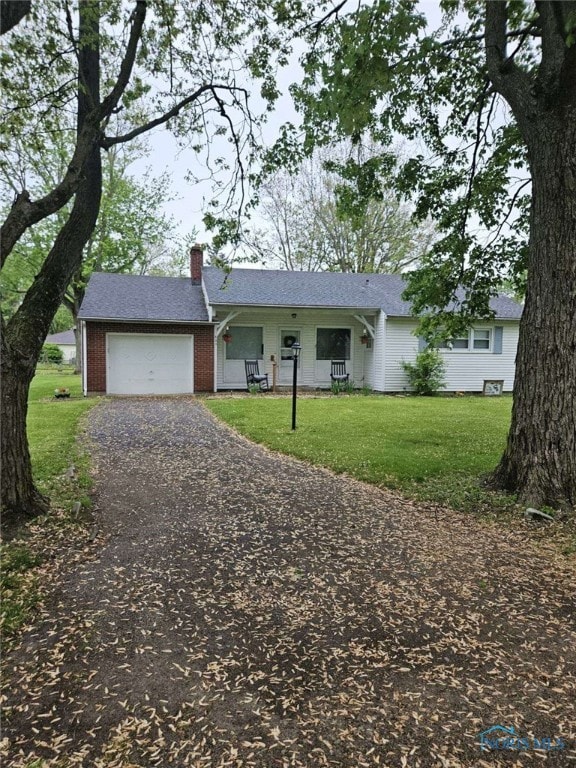 ranch-style house with a chimney, a front lawn, driveway, a garage, and brick siding