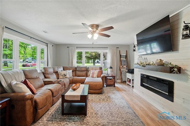 9544 Maumee Western Rd, Monclova, OH 43542 - living area with wood finished floors, a ceiling fan, healthy amount of natural light, a glass covered fireplace, and a textured ceiling