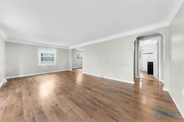 21 Pennsylvania Ave, Waterville, OH 43566 - unfurnished living room featuring arched walkways, hardwood / wood-style floors, and baseboards