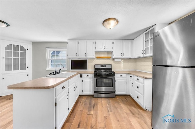 21 Pennsylvania Ave, Waterville, OH 43566 - kitchen featuring stainless steel appliances, a sink, a peninsula, light wood-style flooring, and decorative backsplash