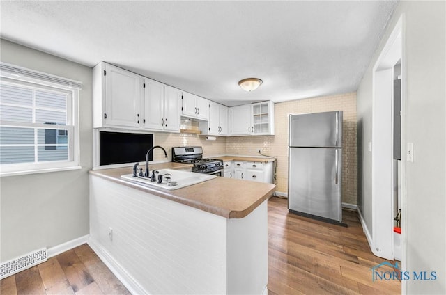 21 Pennsylvania Ave, Waterville, OH 43566 - kitchen with appliances with stainless steel finishes, a peninsula, a sink, wood finished floors, and baseboards