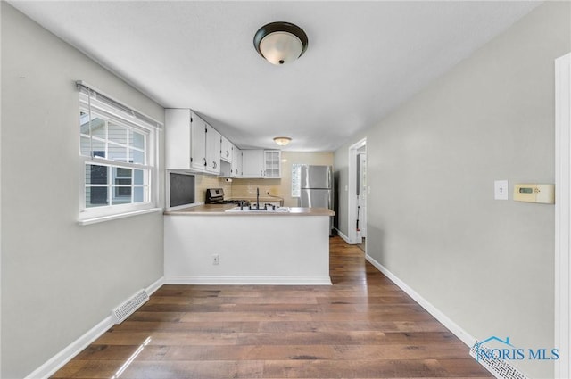 21 Pennsylvania Ave, Waterville, OH 43566 - kitchen featuring dark wood finished floors, appliances with stainless steel finishes, a peninsula, glass insert cabinets, and white cabinetry