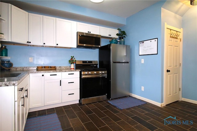 kitchen featuring stainless steel appliances, white cabinets, baseboards, and wood tiled floors