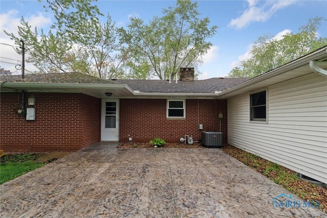1208 Lindau St, Archbold, OH 43502 - view of exterior entry with a patio, a chimney, brick siding, and central air condition unit