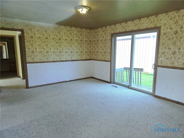 5924 N Reiman Rd, Curtice, OH 43412 - spare room with wallpapered walls, carpet flooring, baseboards, and wainscoting