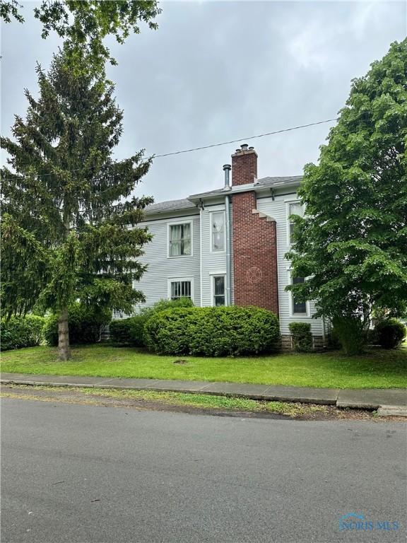 202 E Montford Ave, Ada, OH 45810 - view of side of home featuring a chimney and a lawn