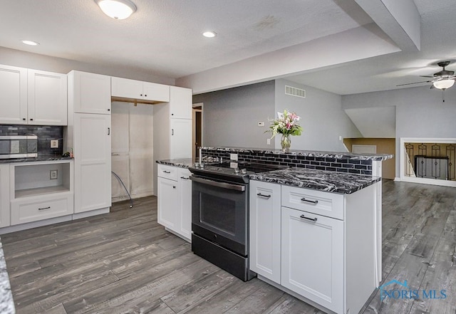 17315 County Road R, Napoleon, OH 43545 - kitchen with stainless steel microwave, black electric range, tasteful backsplash, dark stone counters, and white cabinetry