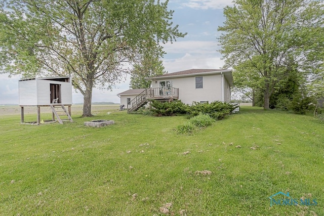17315 County Road R, Napoleon, OH 43545 - view of green lawn featuring a fire pit, a wooden deck, stairway, and an outbuilding