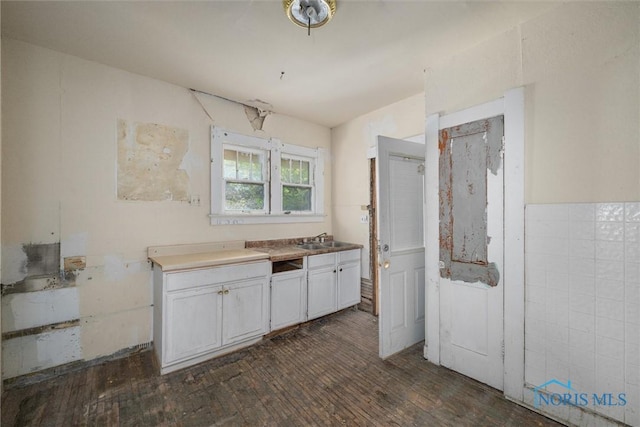 kitchen with a sink, dark wood-style floors, and white cabinetry