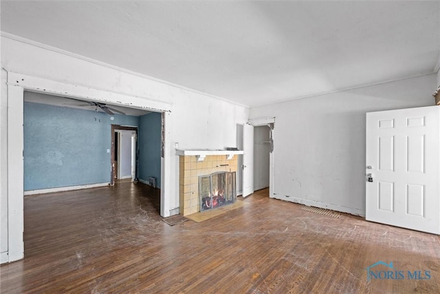 unfurnished living room featuring wood finished floors, a tile fireplace, and baseboards