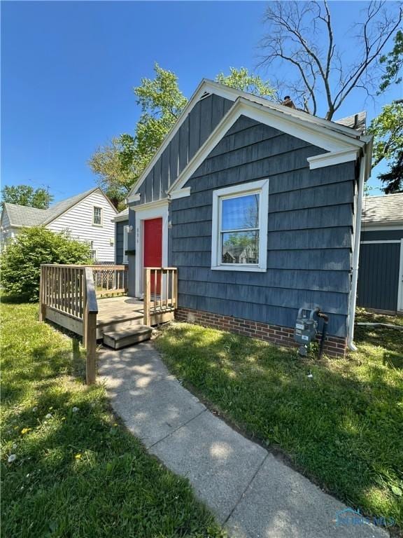 bungalow-style home with a wooden deck, board and batten siding, and a front yard