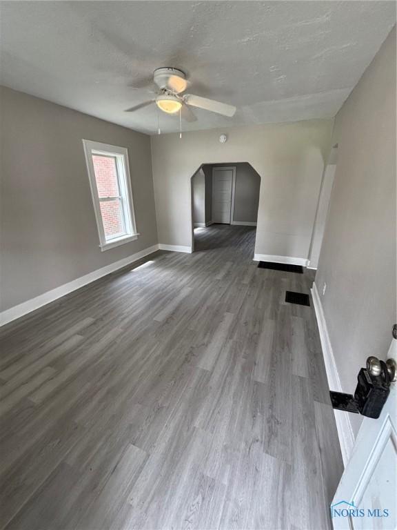 3907 Lagrange St, Toledo, OH 43612 - unfurnished living room featuring ceiling fan, baseboards, dark wood finished floors, and arched walkways