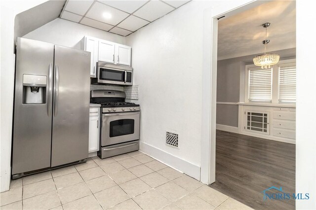 4202 Asbury Dr, Toledo, OH 43612 - kitchen featuring stainless steel appliances, white cabinets, baseboards, decorative light fixtures, and light tile patterned floors
