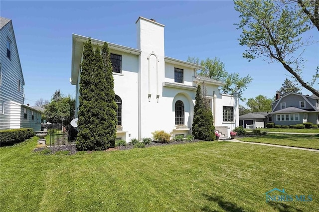 218 E Mcpherson Ave, Findlay, OH 45840 - mediterranean / spanish house featuring a front lawn, a chimney, and stucco siding