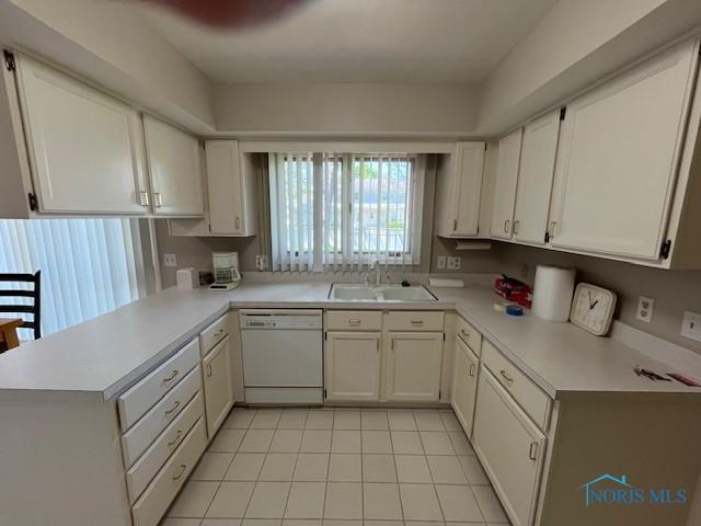6047 Peppermill Dr, Sylvania, OH 43560 - kitchen featuring white dishwasher, a sink, light countertops, a peninsula, and light tile patterned flooring