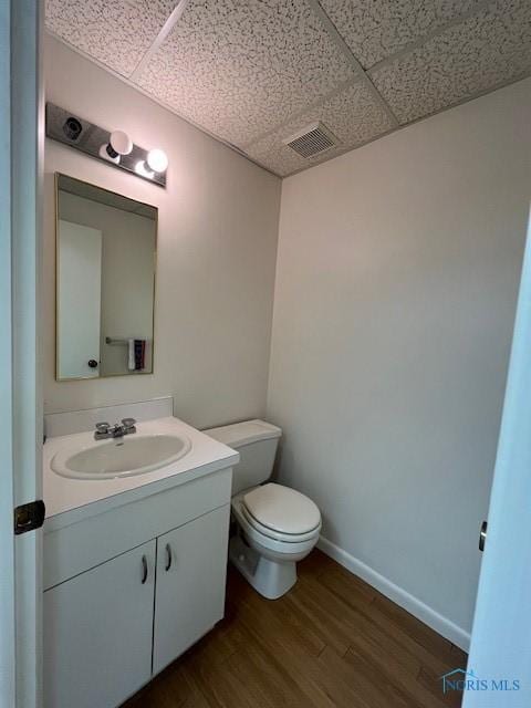 6047 Peppermill Dr, Sylvania, OH 43560 - half bath featuring a paneled ceiling, wood finished floors, vanity, toilet, and baseboards
