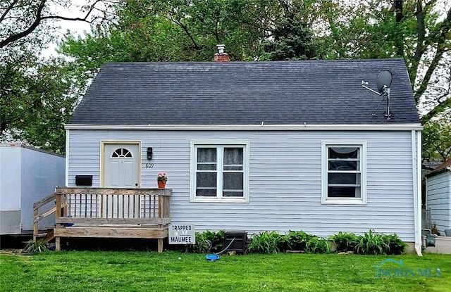 view of front of home featuring a front lawn, a chimney, a wooden deck, and a shingled roof