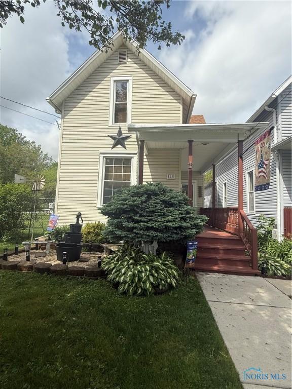 115 N Beecher St, North Baltimore, OH 45872 - view of front of house featuring covered porch and a front lawn