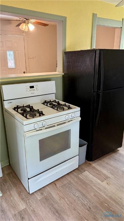 2659 Oak Grove Pl, Toledo, OH 43613 - kitchen with white range with gas stovetop, light wood finished floors, freestanding refrigerator, and a ceiling fan
