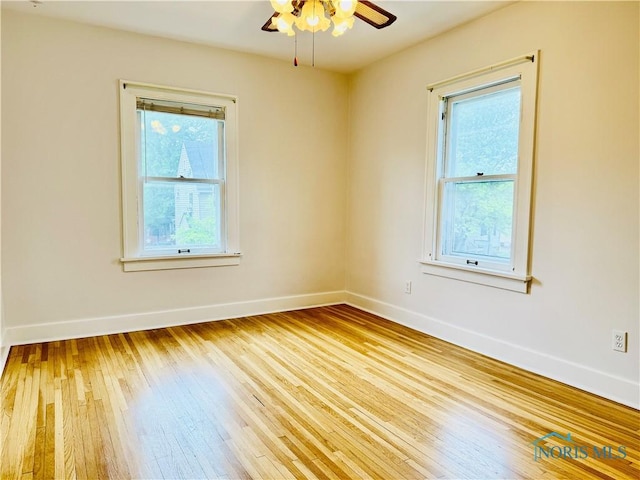 spare room with hardwood / wood-style flooring, baseboards, and a ceiling fan