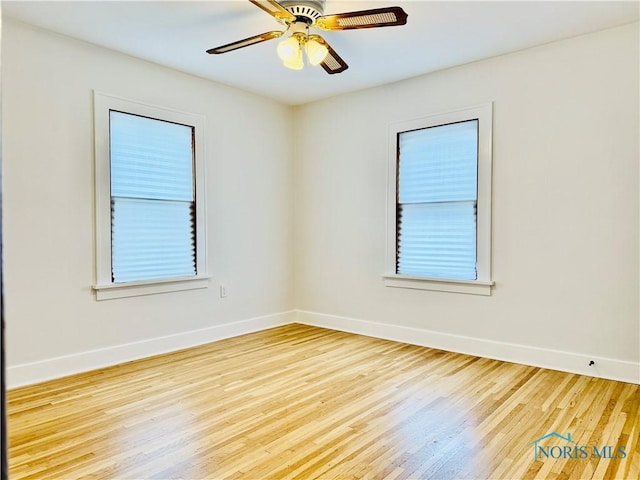 spare room with baseboards, wood finished floors, and ceiling fan