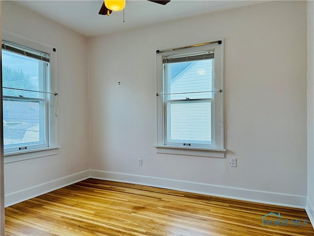 empty room featuring baseboards, a ceiling fan, light wood-type flooring, and plenty of natural light