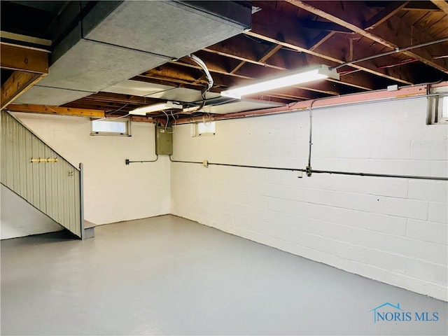 basement with concrete block wall and electric panel