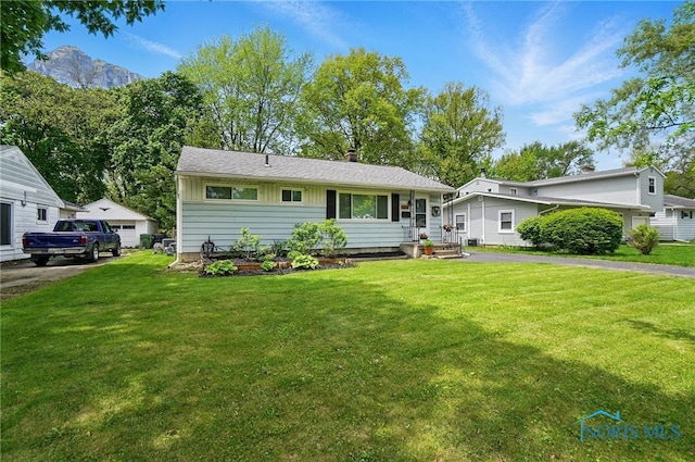 view of front of home with a front lawn, a chimney, a detached garage, and board and batten siding