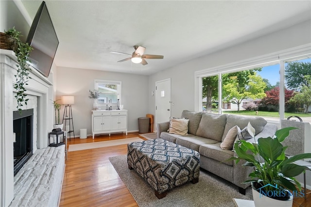 living area featuring a premium fireplace, a ceiling fan, and wood finished floors