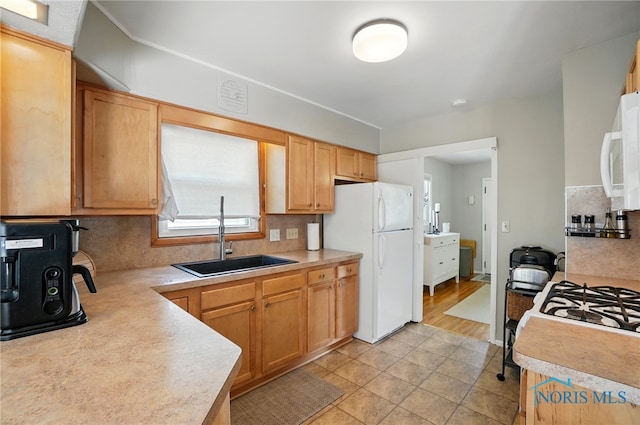 kitchen with white appliances, light countertops, decorative backsplash, and a sink