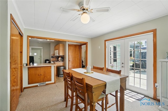dining area featuring light carpet, a ceiling fan, and french doors