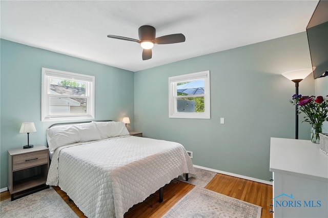 bedroom with multiple windows, wood finished floors, baseboards, and ceiling fan