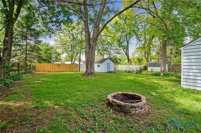 view of yard with a storage unit, an outdoor fire pit, and an outdoor structure