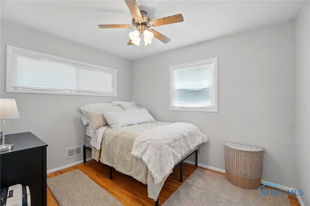 bedroom featuring multiple windows, baseboards, and wood finished floors