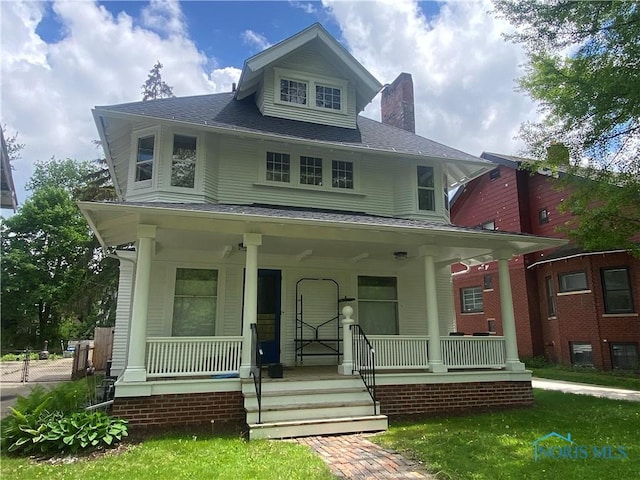 traditional style home with a porch, a shingled roof, and a chimney