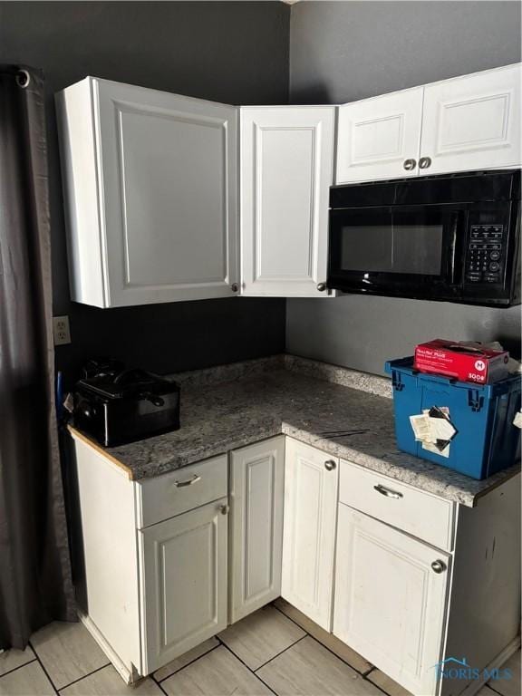 315 Austin St, Toledo, OH 43608 - kitchen with black microwave, white cabinetry, and light tile patterned floors