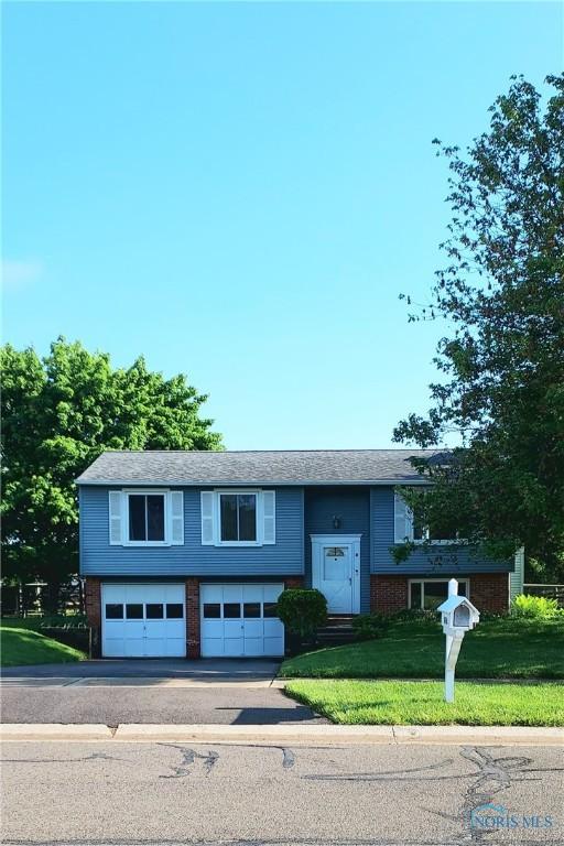 856 Village Pkwy, Waterville, OH 43566 - raised ranch with an attached garage, driveway, brick siding, and a front yard