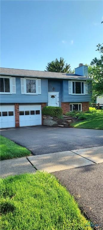 856 Village Pkwy, Waterville, OH 43566 - bi-level home with an attached garage, asphalt driveway, a chimney, and brick siding